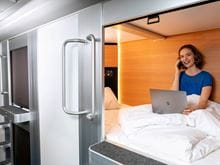 Woman sitting on a bed in one of the sleeping pods